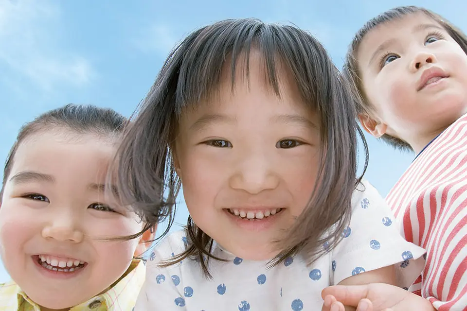 3人の子供達が手を繋いで笑う様子