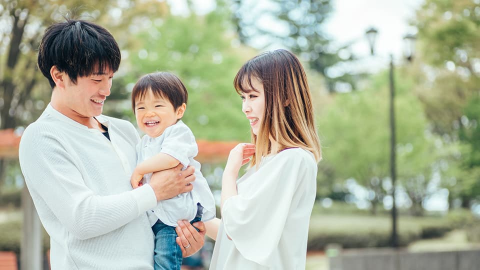 公園で子供を抱き笑顔の夫婦