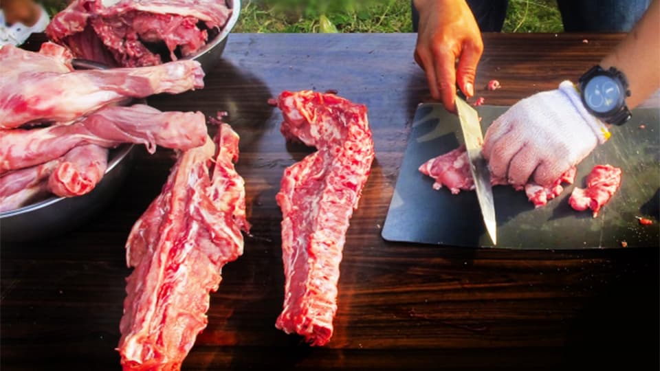 屋外で大きな肉を切る光景