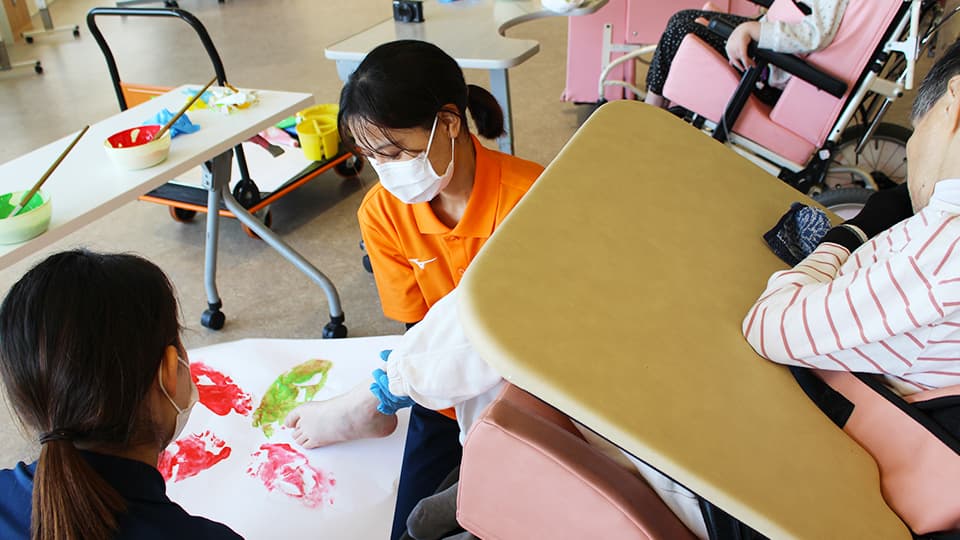 絵の具で遊ぶ利用者を手伝う様子
