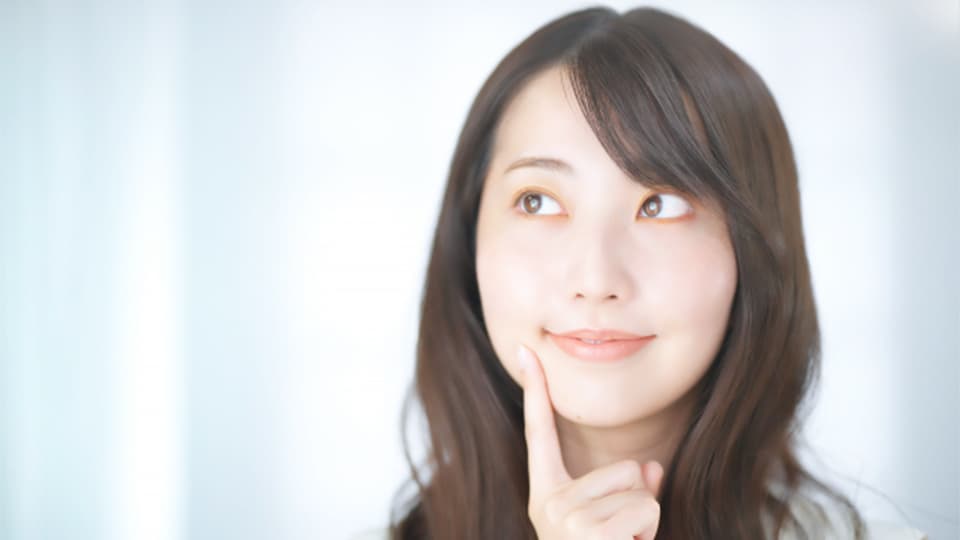 頬に指を当てて考える女性