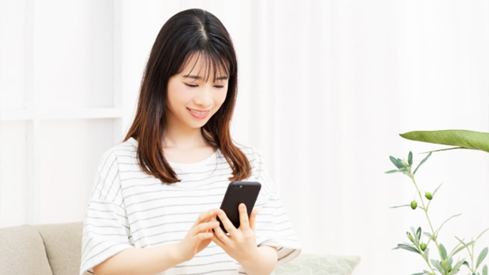 座ってスマートフォンを見る若い女性