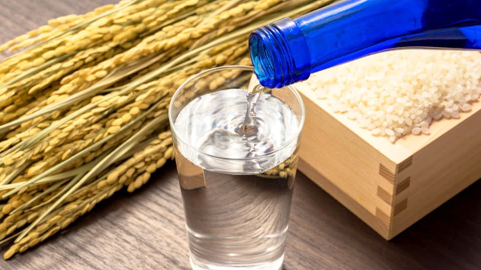 升に入った米とグラスに注がれる日本酒