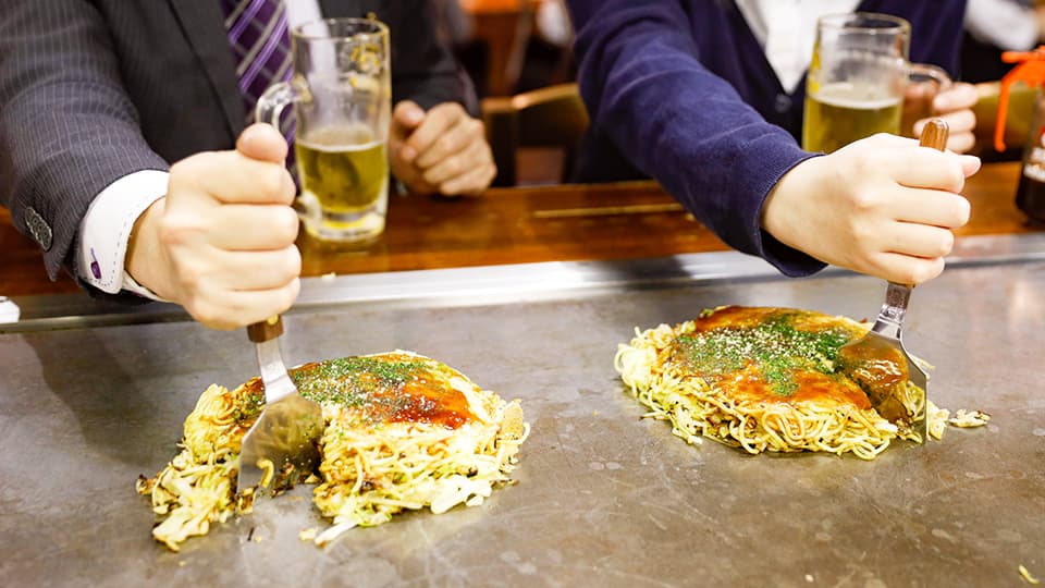 広島のお好み焼きを食べるふたり