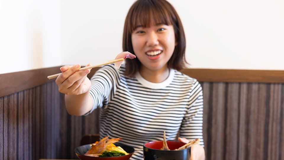 箸で刺身を持つ女性