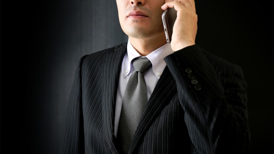 電話をかける黒スーツの男