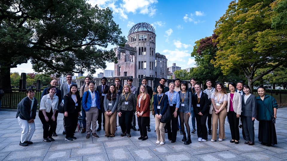 様々な国の人々が原爆ドーム前で集合写真を撮る様子