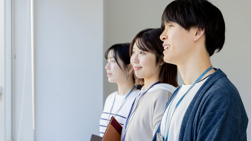 窓の外を笑顔で眺める3人の男女