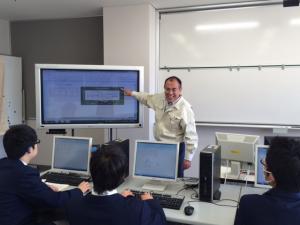 生徒がパソコン画面を見てパソコン操作の学習をしている。教師は電子黒板を使用し説明。