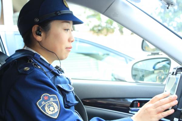 パトカーの中で機械を操作する女性警察官