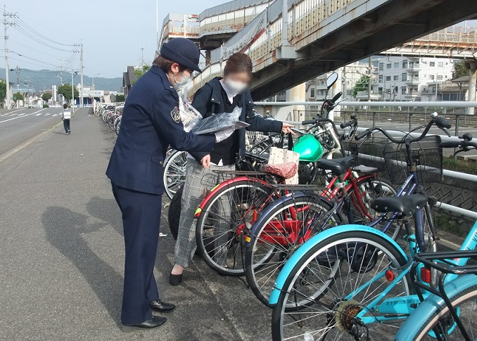 自転車の防犯チラシを配る警察官