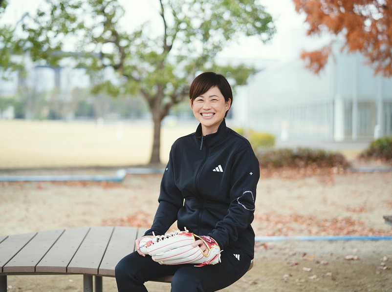 公園のベンチに座り野球のグローブをしている笑顔の女性