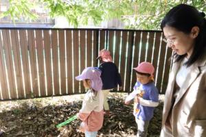 落ち葉を集める子供を見守る小田原委員