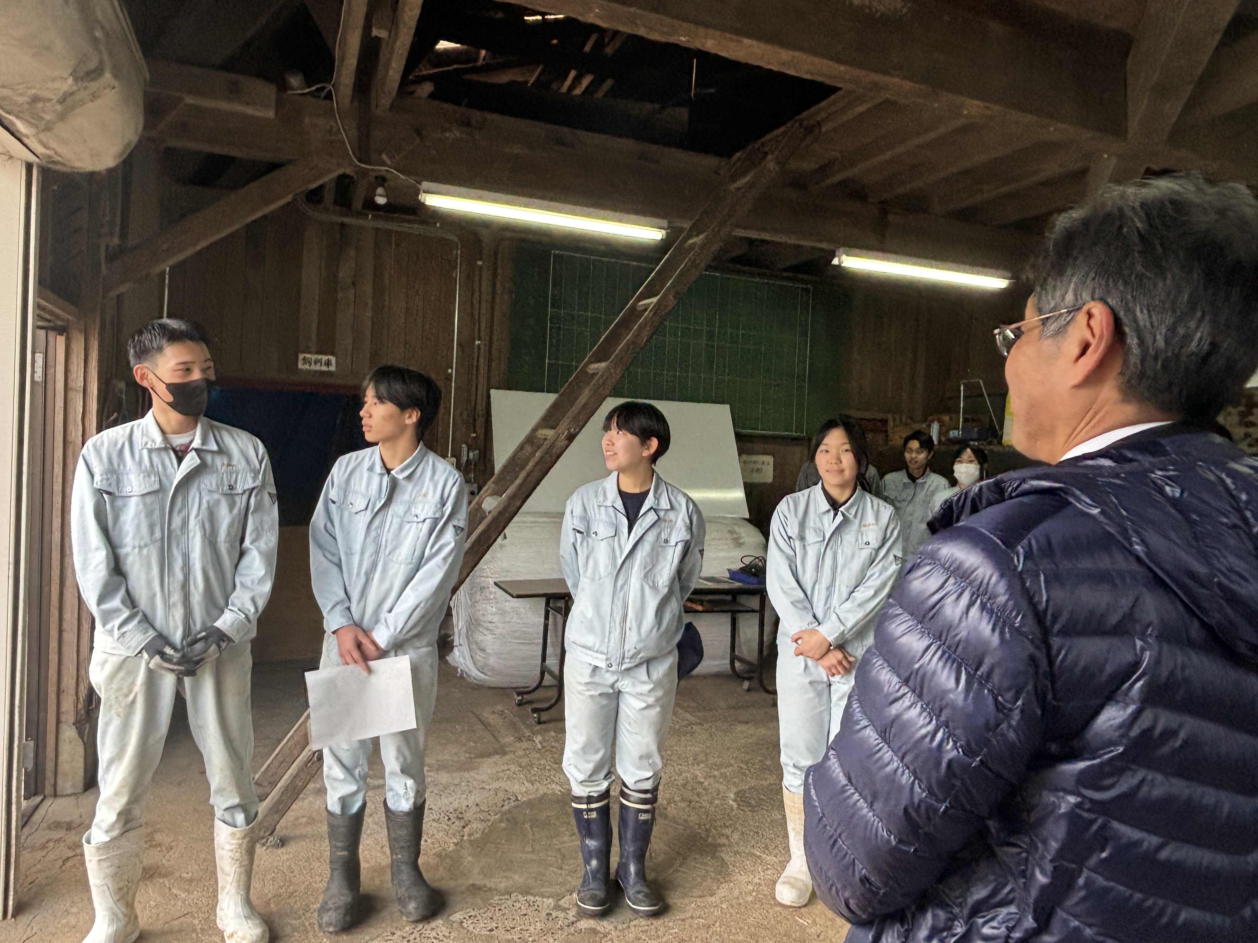 牛舎の中で畜産班と挨拶をするようす