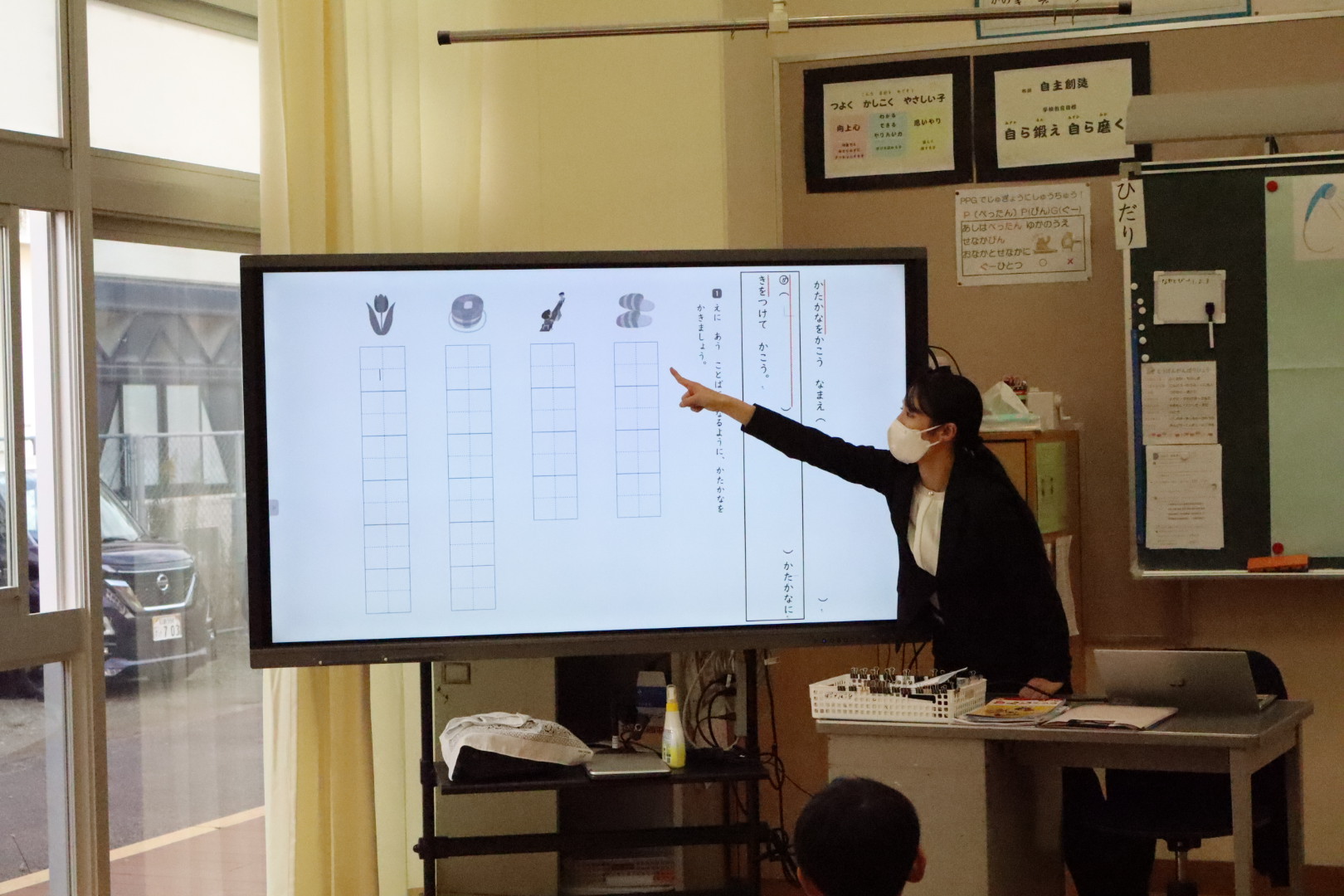 教員がモニターを指さしながら説明をする様子