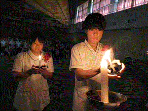 学生が校長先生から火を受け継いでいる
